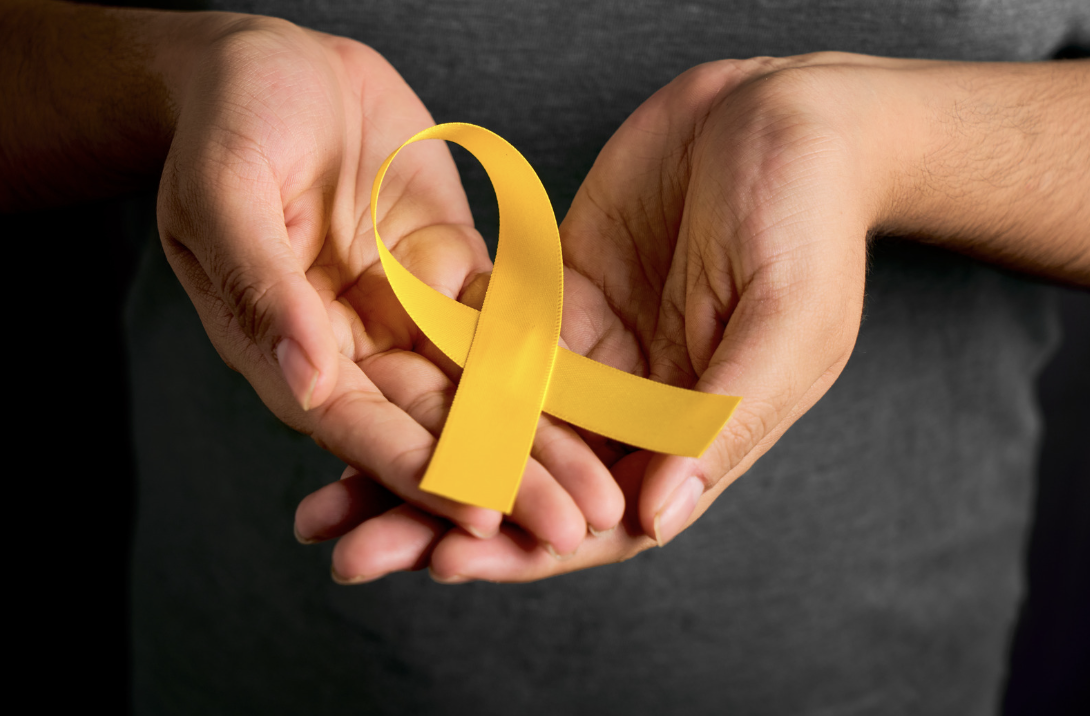 Photo of hands palm up, holding a yellow suicide prevention ribbon